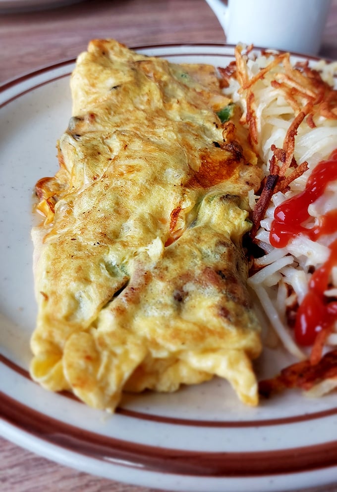 Behold, the omelet of your dreams! Fluffy eggs embrace a medley of fillings, while crispy hash browns stand guard. A breakfast worth waking up for.