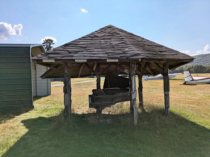 A rustic gazebo that's seen better days, but hey, it's got more character than a soap opera marathon. Pull up a log and stay awhile!