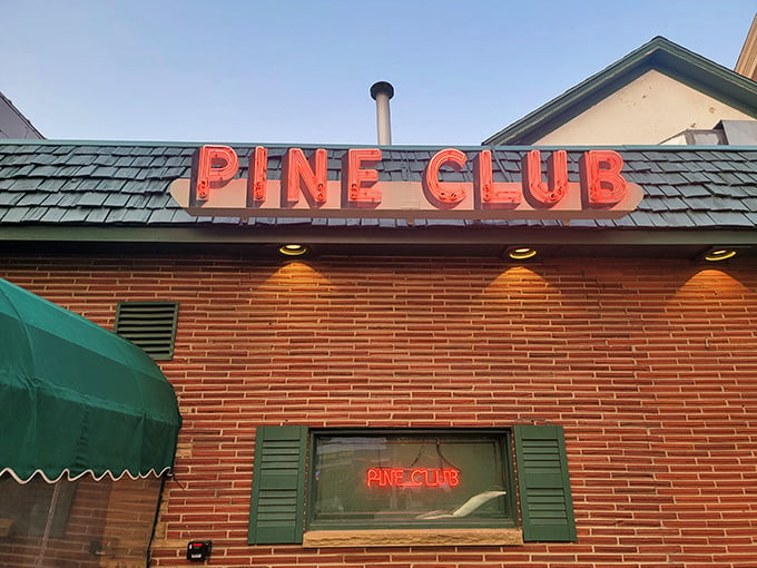 "The Pine Club's neon sign: a beacon of hope for the hungry. It's like a lighthouse, but instead of ships, it guides steaks to your table."