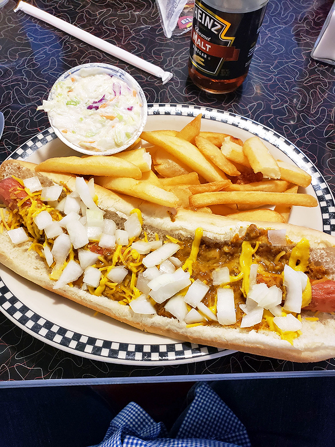 The holy trinity of diner delights! A Coney dog, crispy fries, and a creamy shake – it's like the 1950s wrapped up in a checkered paper.