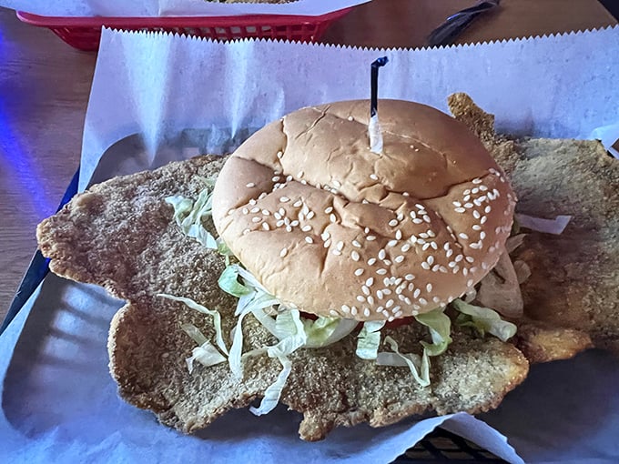 This isn't just a sandwich; it's a feat of culinary engineering. The bun's playing hide-and-seek with a tenderloin that's auditioning for a role in "Honey, I Shrunk the Pig!"