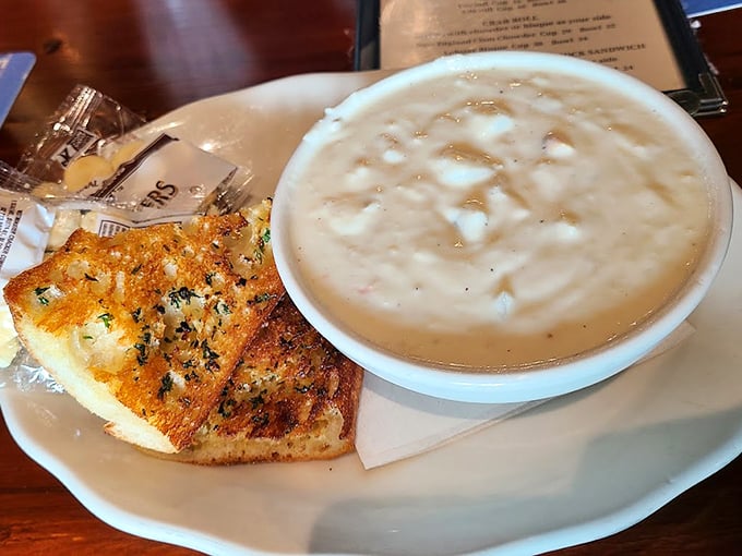 Creamy New England clam chowder pairs with garlic bread, creating the kind of comfort that makes rainy days worthwhile.