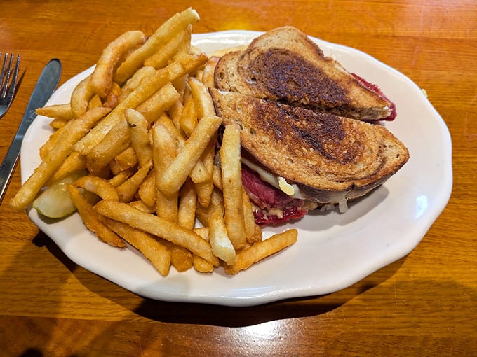 This classic Reuben, grilled to perfection, shares its plate with a generous helping of crispy fries.