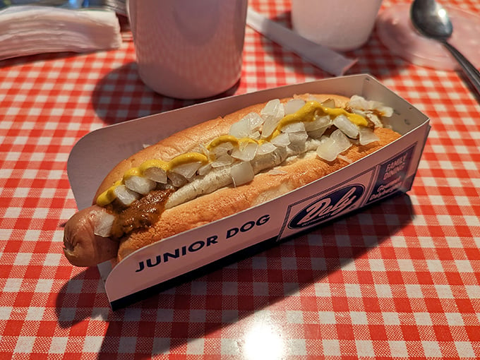 Holy hot dog, Batman! This "Junior Dog" is anything but small. Nestled in its paper cradle, it's a symphony of savory toppings that'll make your taste buds dance.