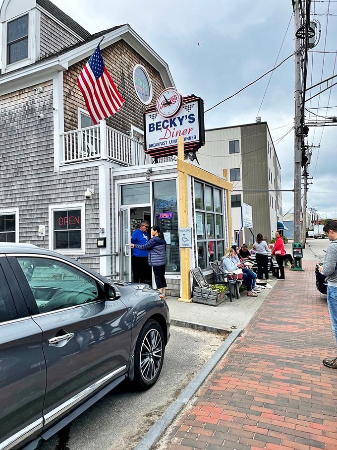 A weathered American flag waves proudly above Becky's iconic sign, while hungry patrons patiently wait their turn for Maine's beloved comfort food. Photo credit: Annie C.